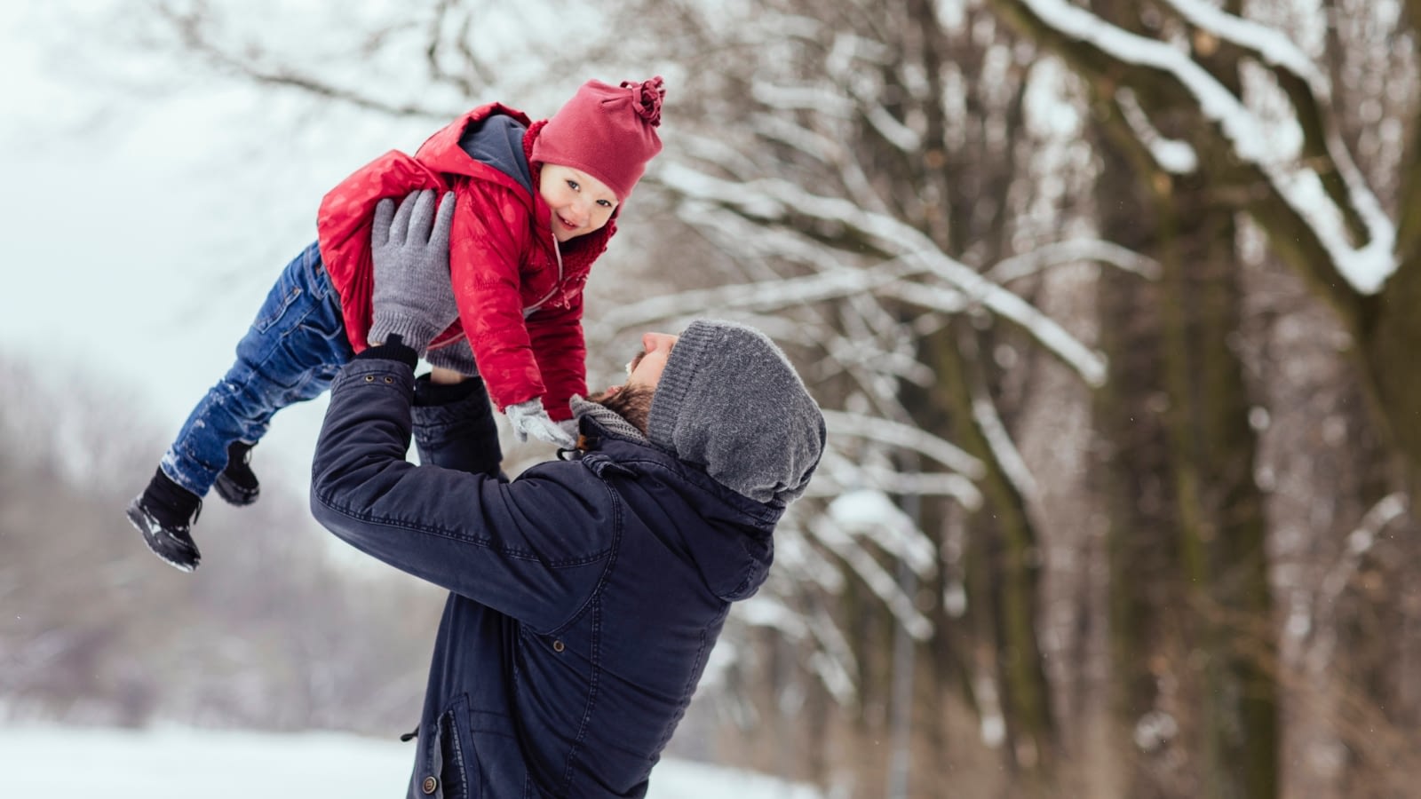 father holding up son in snow