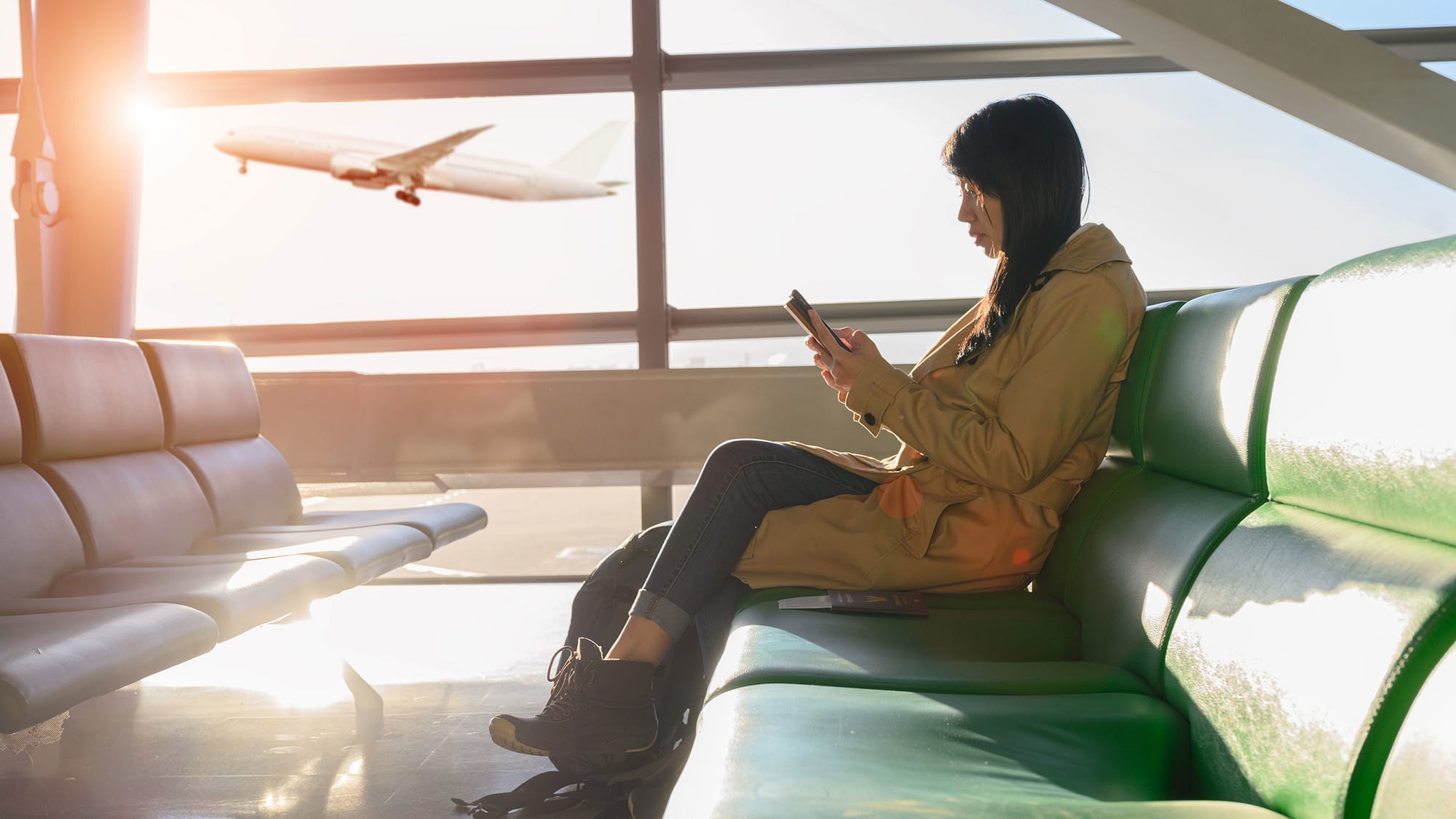 Female waiting in the airport with airplane departing in the background.