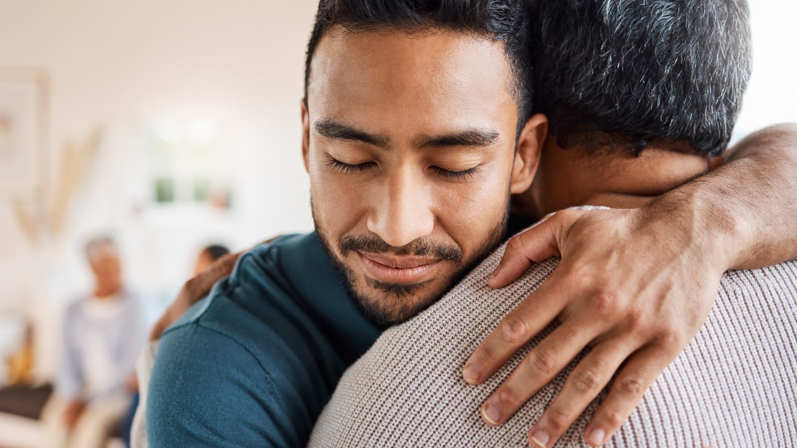 Younger man embracing older man Man hugging father