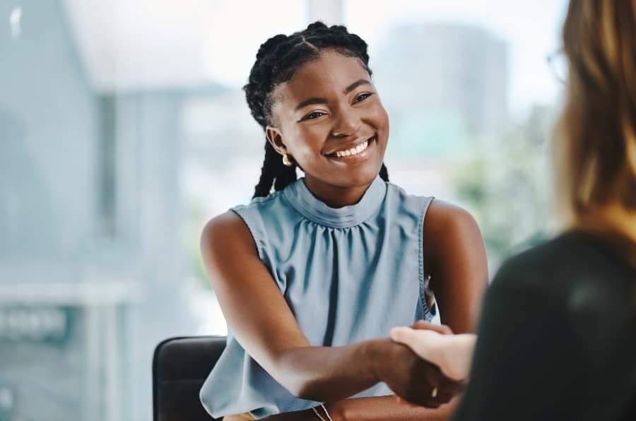 Confident Young Woman Confident young African businesswoman shaking hands with a colleague in an office