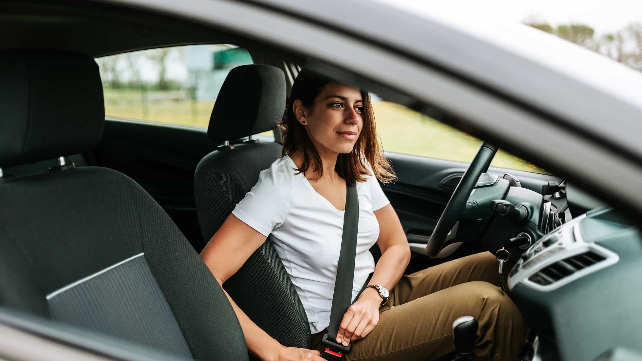 Female driver buckling the seatbelt in her car.