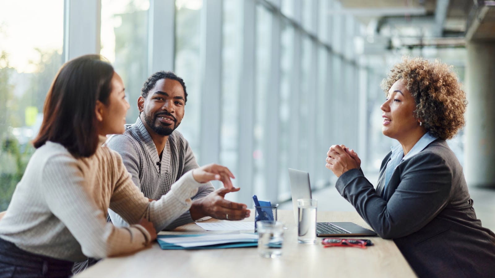 Happy diverse couple talking to an agent
