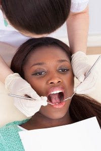 Dentist Examining a Young Woman's Teeth During a Dental Appointment