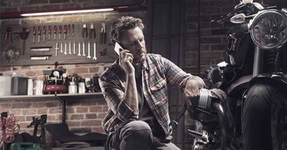 guy_talking_on_phone_next_to_motorcycle_575x300