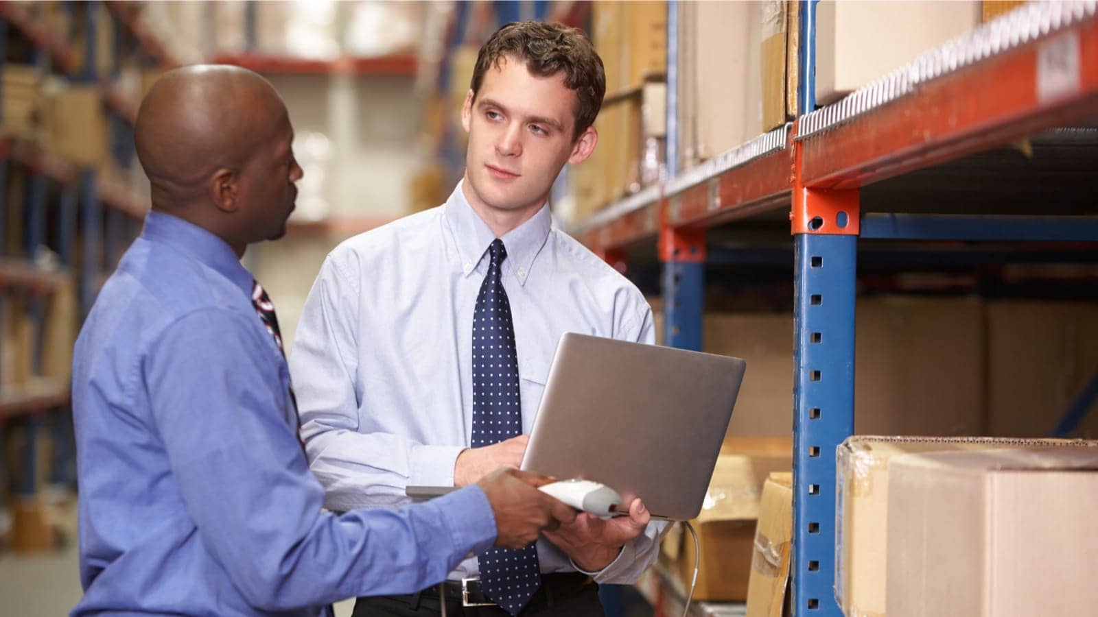men in warehouse speaking and looking at a tablet