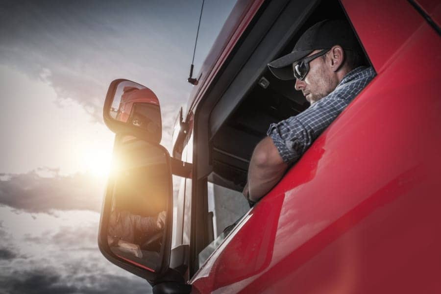 Man looking out the window of a semi truck cab