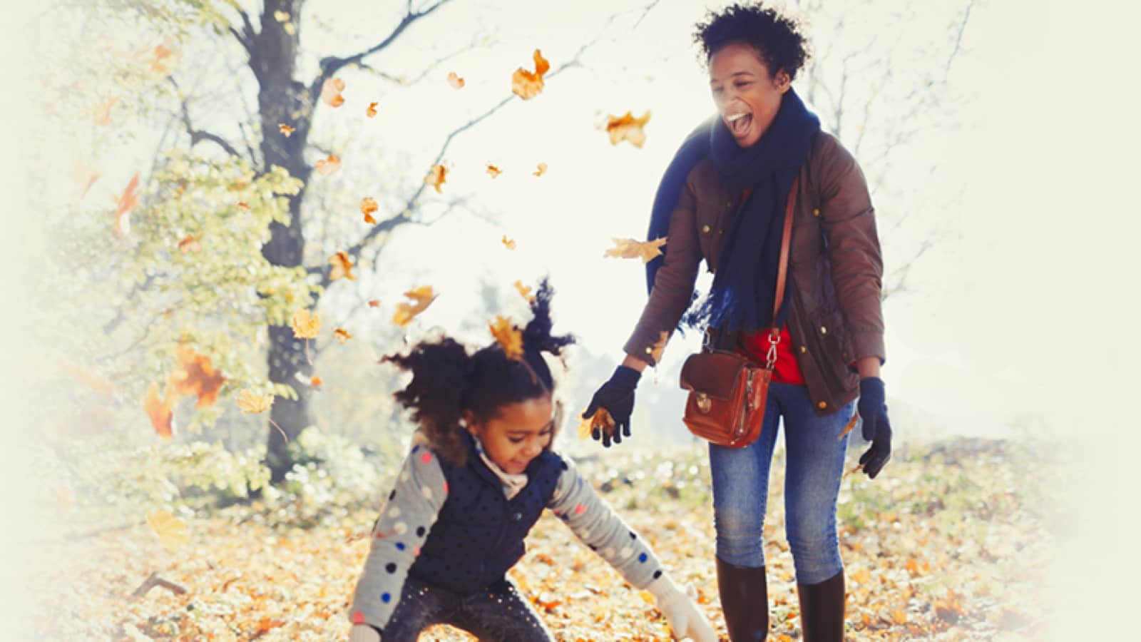 Mother and daughter playing in falling leaves