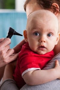 Baby Looks at Camera as his Parent Holds him While a Doctor Examines his Ear