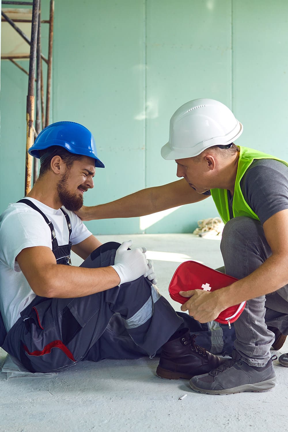 Construction worker tending to injured co-worker on a job site.