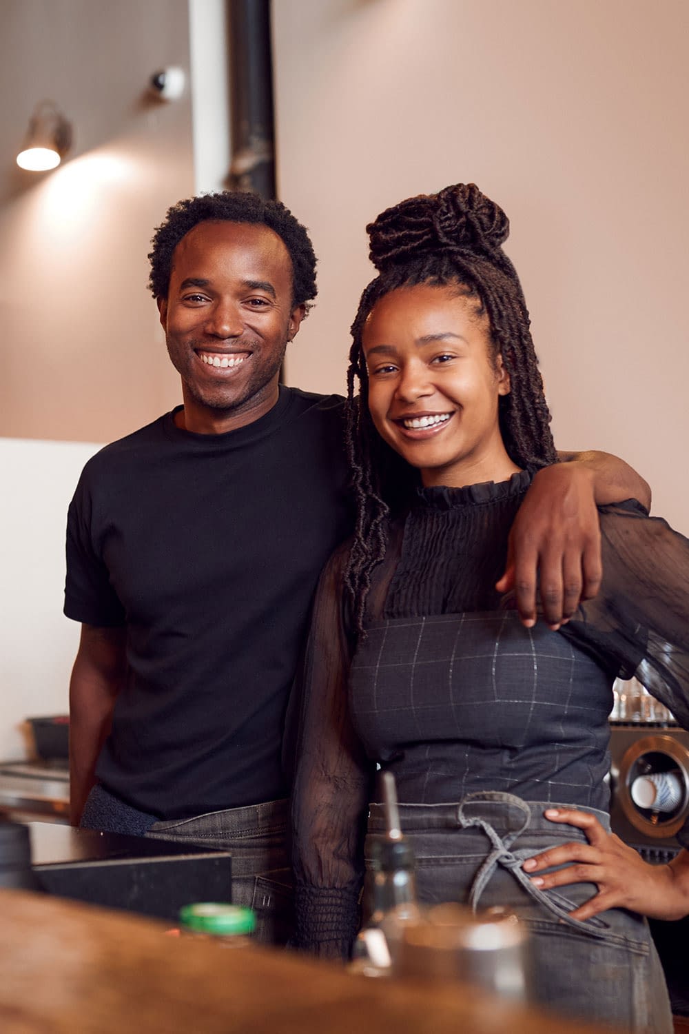 Young business owners behind counter of their coffee shop.