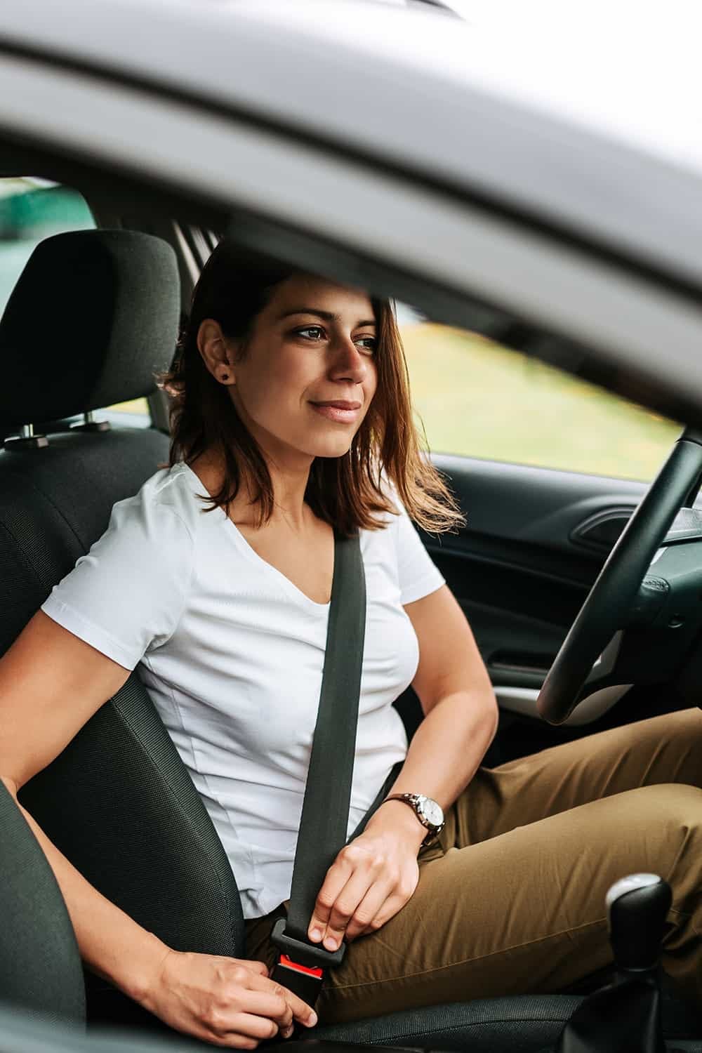 Female driver buckling the seatbelt in her car.