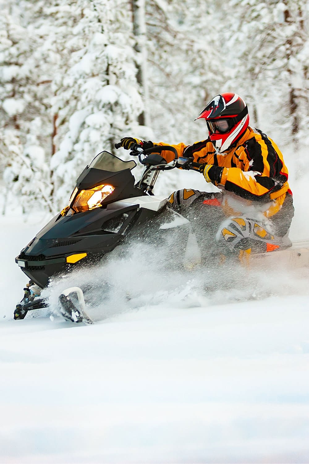 Person riding a snowmobile in snowy landscape.