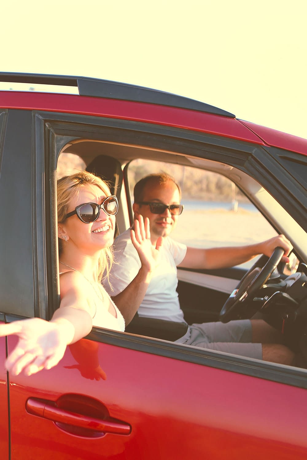 Family riding in a red car waving out the windows.