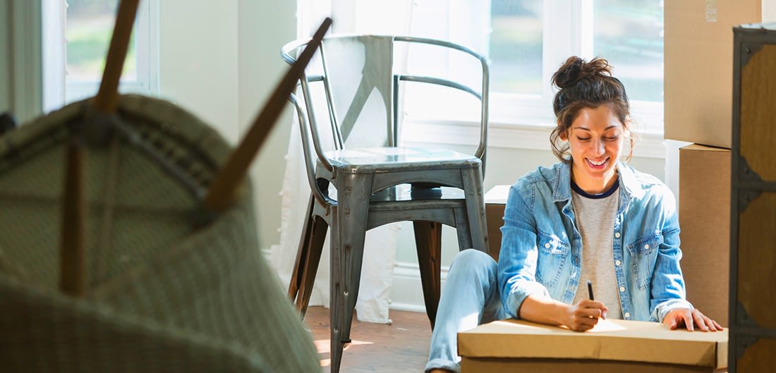 young woman sitting in new apartment on floor