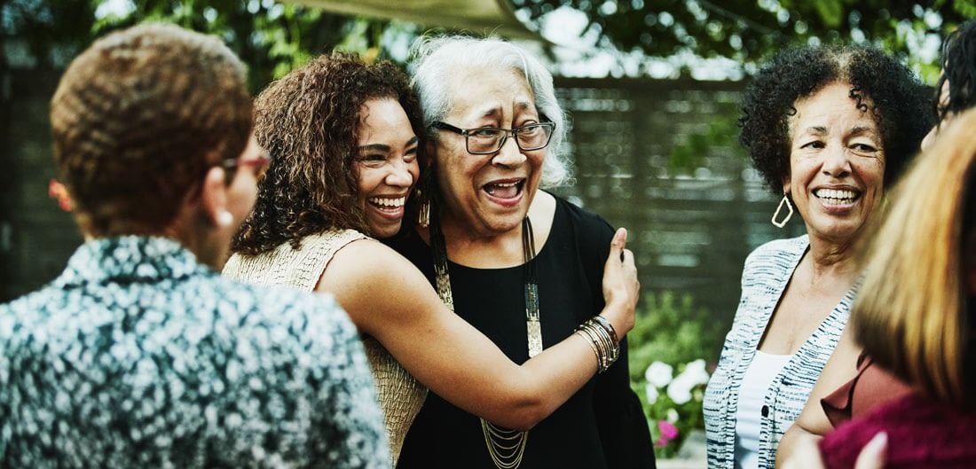 young woman hugging her grandmother among family