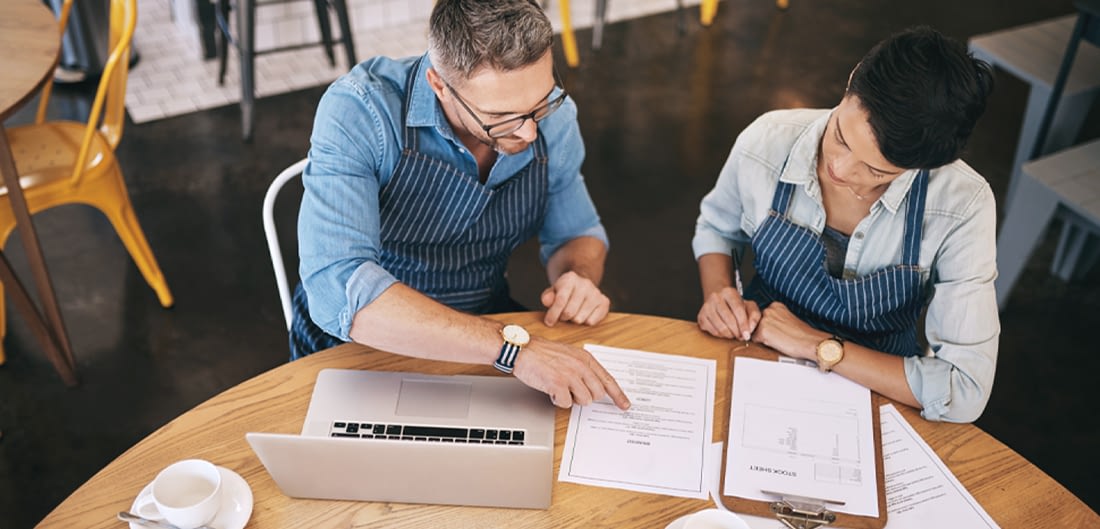 small business owners talking shop at a desk with paperwork