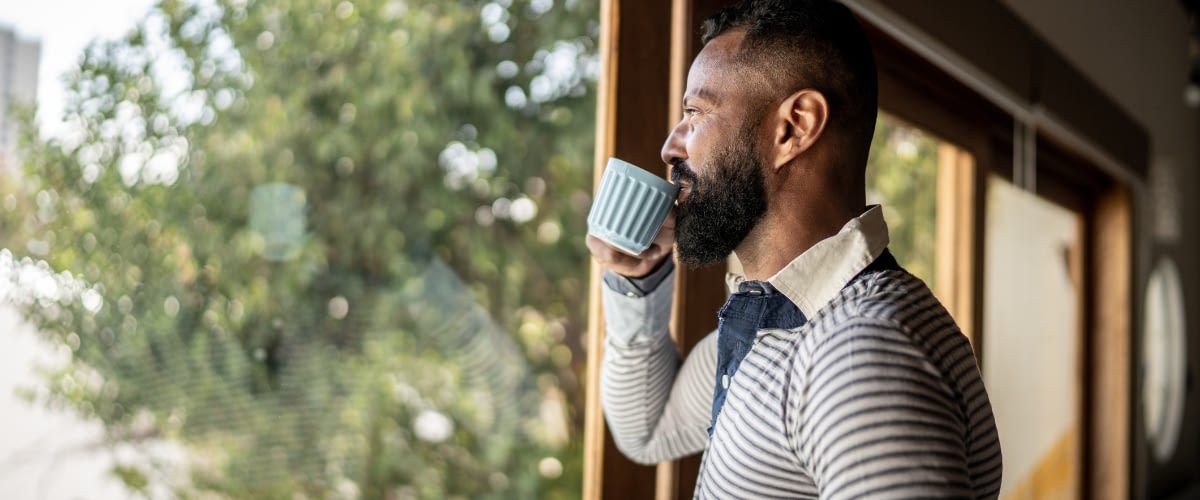 Man sipping coffee and looking out window.