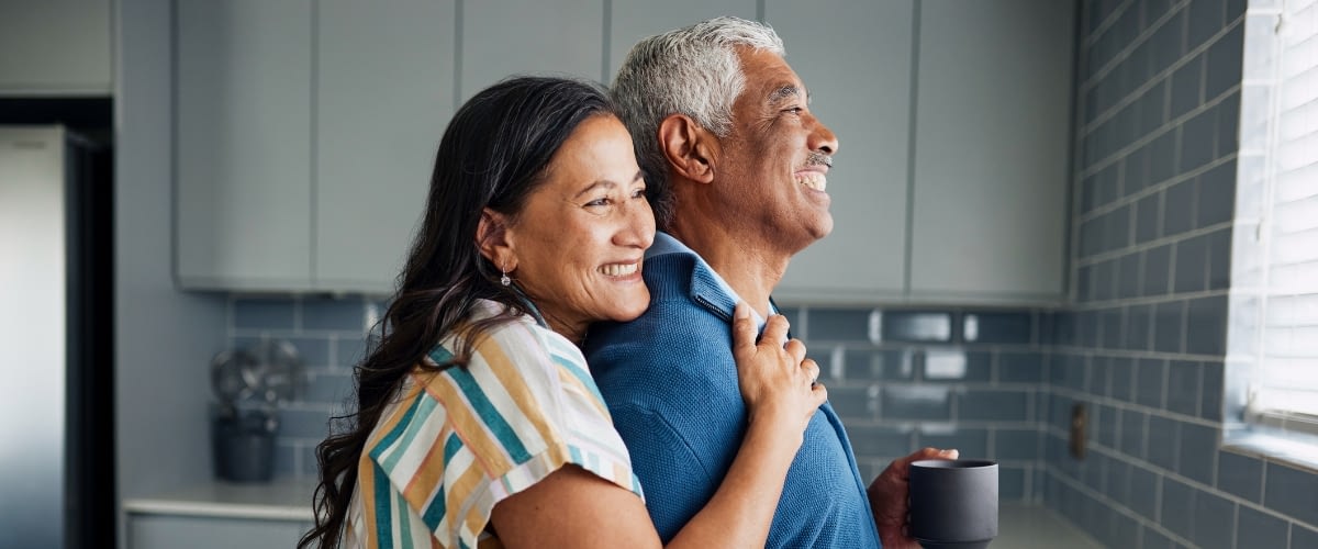 Older couple looking out window and smiling.
