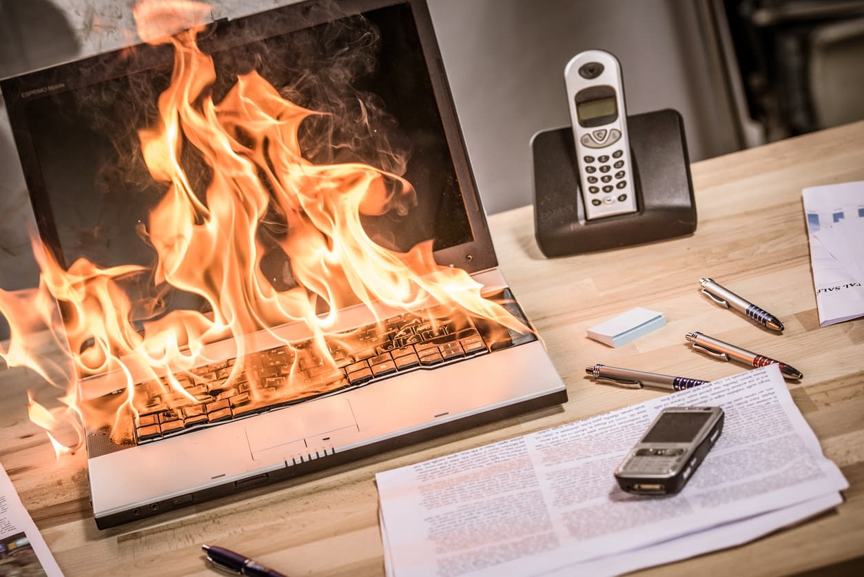 The Growing Danger of Lithium-Ion Battery Fires Burning laptop on desk in office