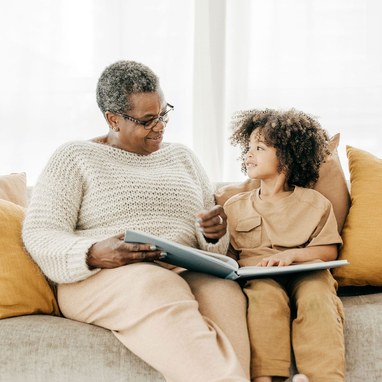 Grandmother or older woman smiling at a child while reading a storybook together