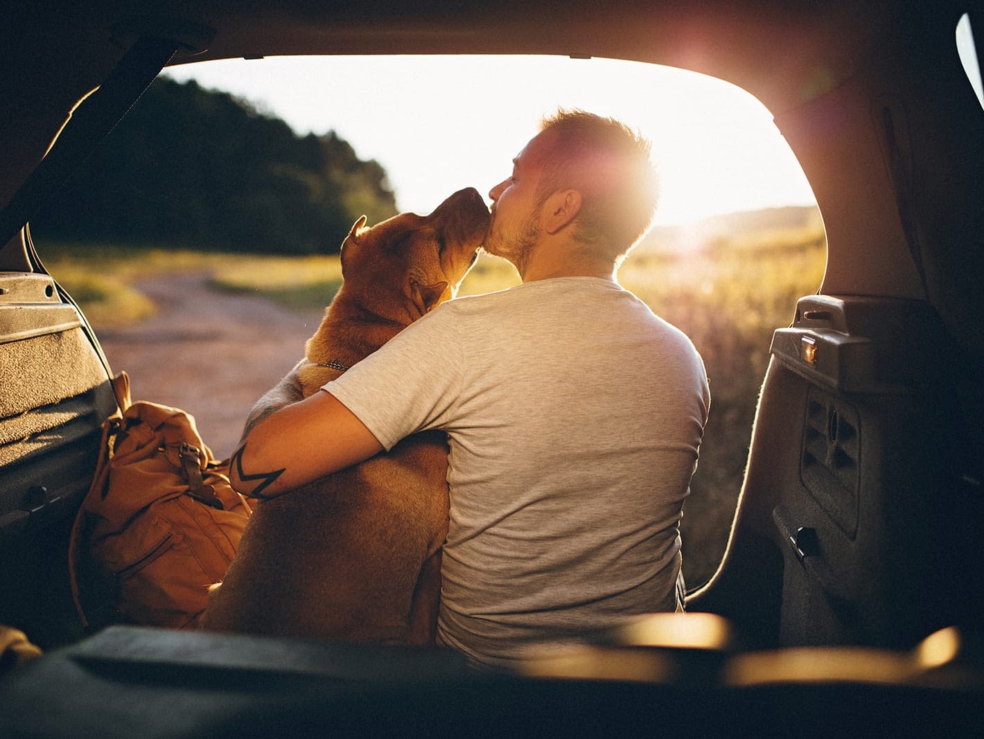 man sitting on car holding dog