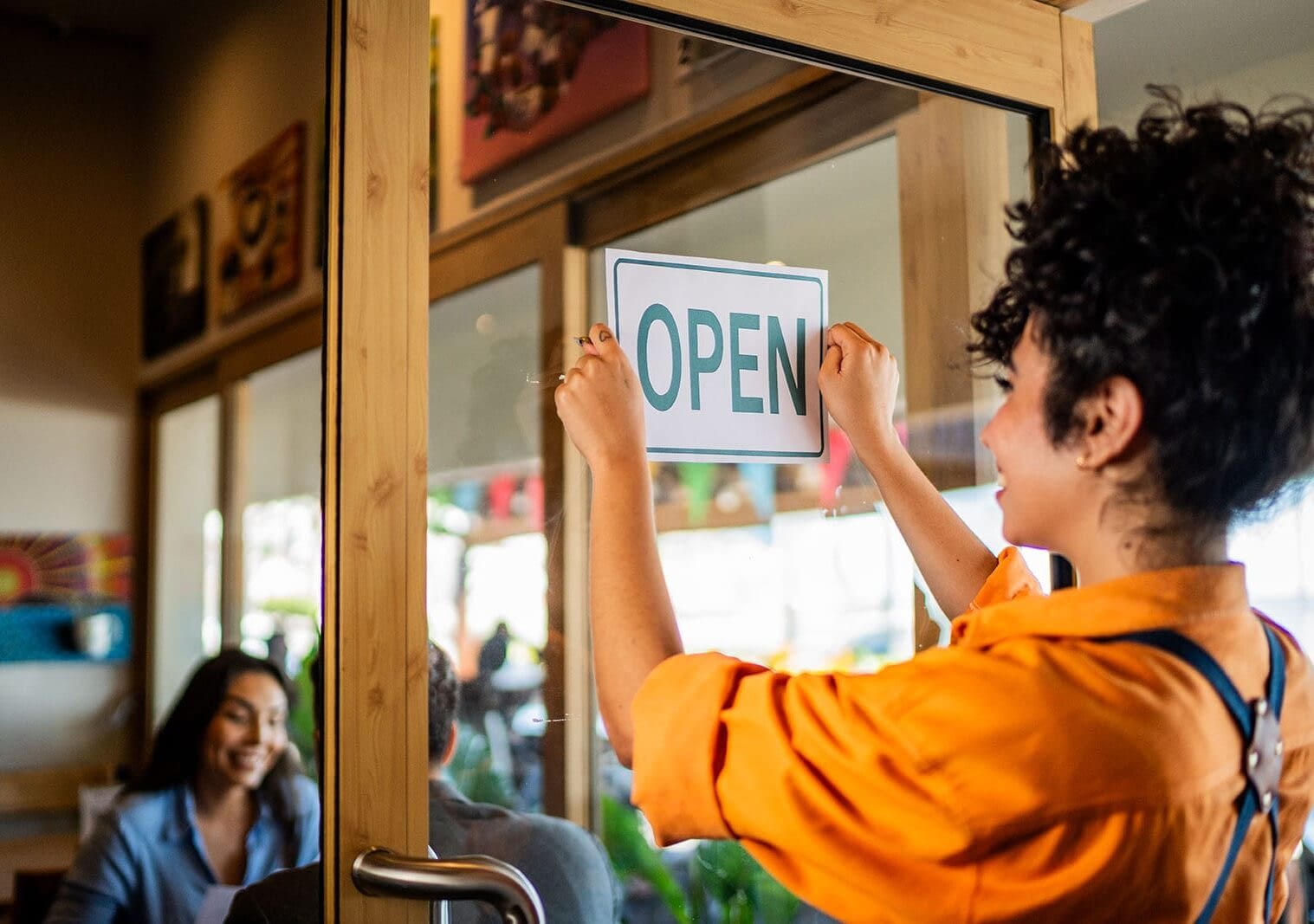 Young waitress gluing open door sign at coffee shop
