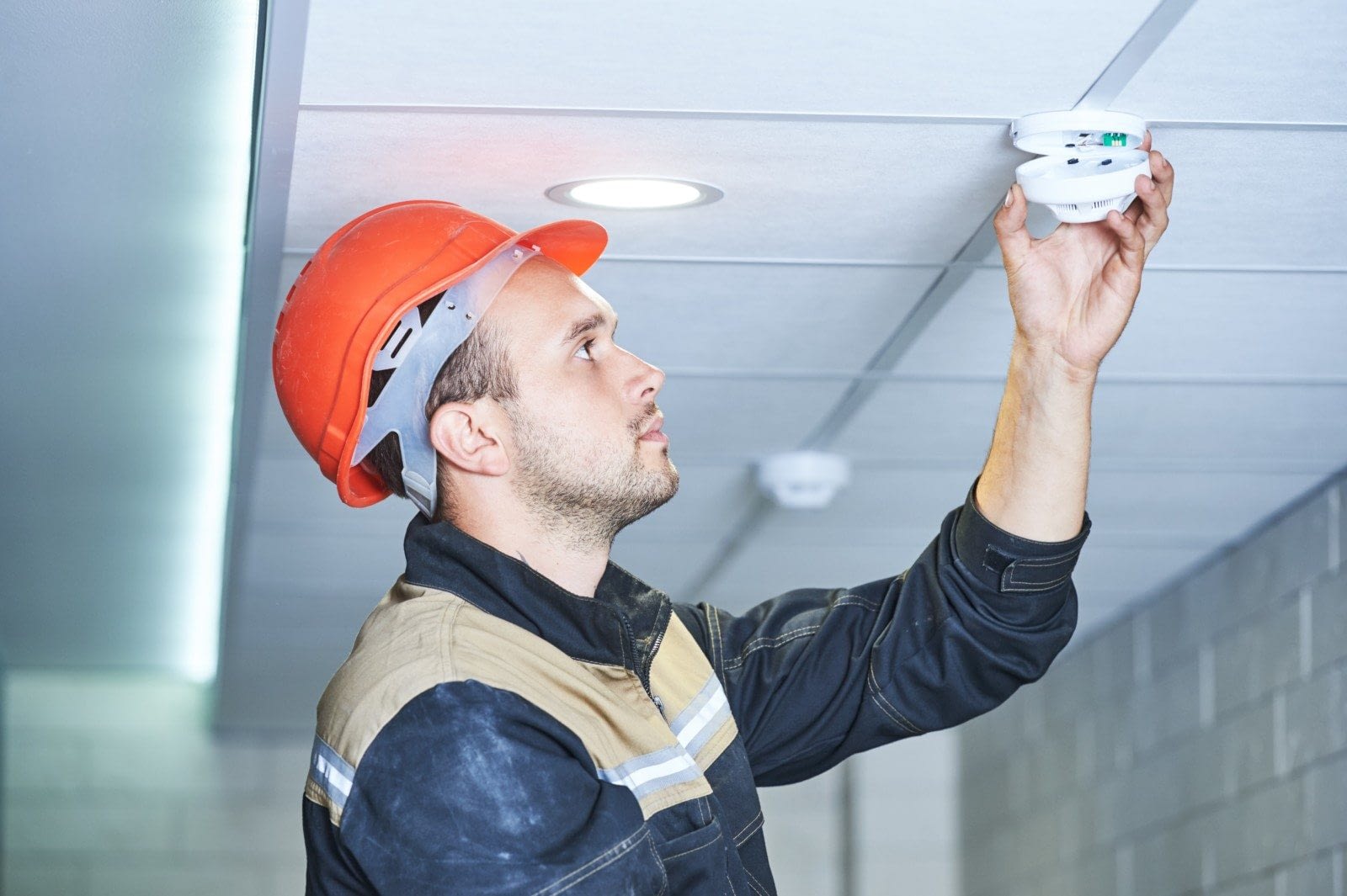 worker installing smoke detector on the ceiling Know where your fire detectors are!