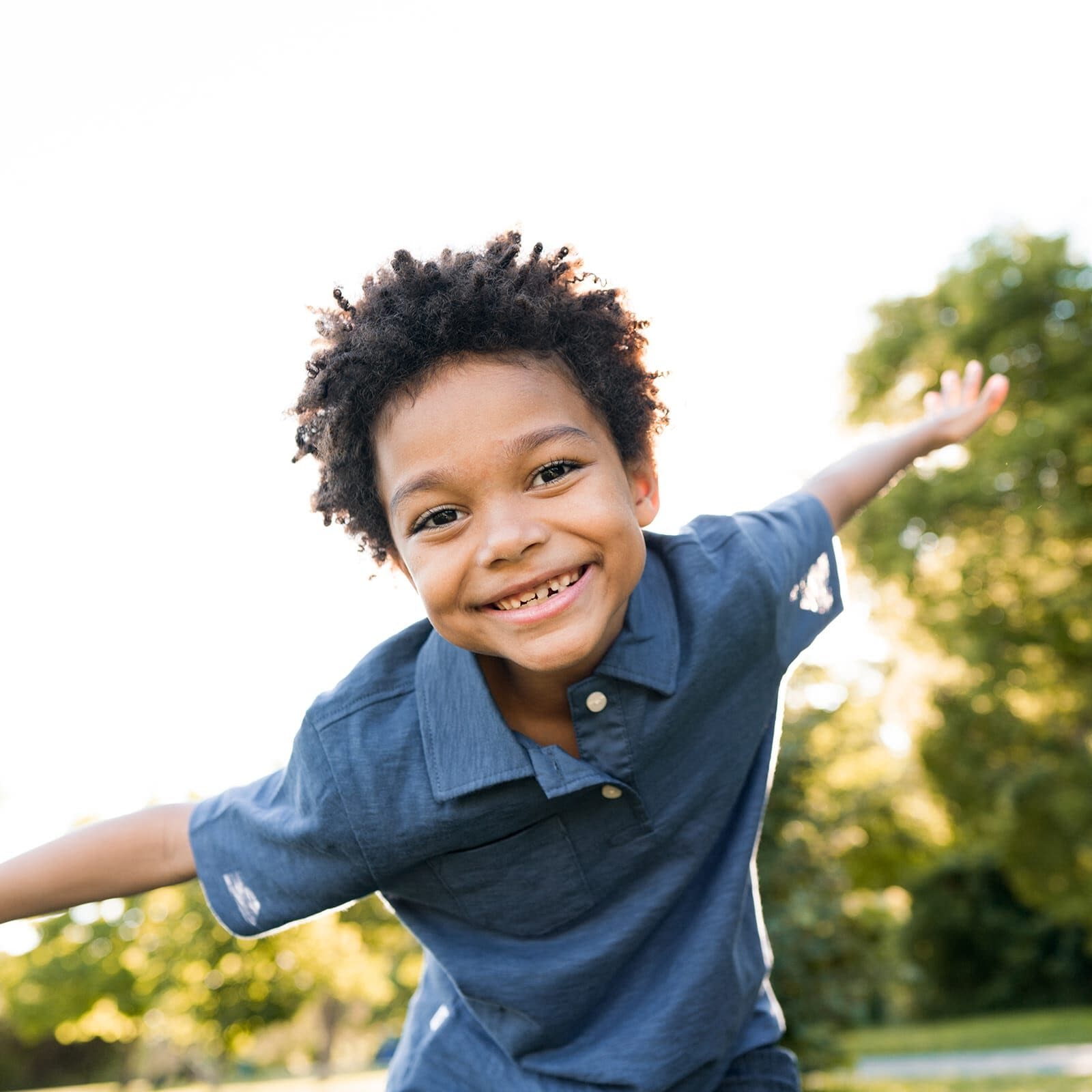 Little boy with curly black hair playing outside