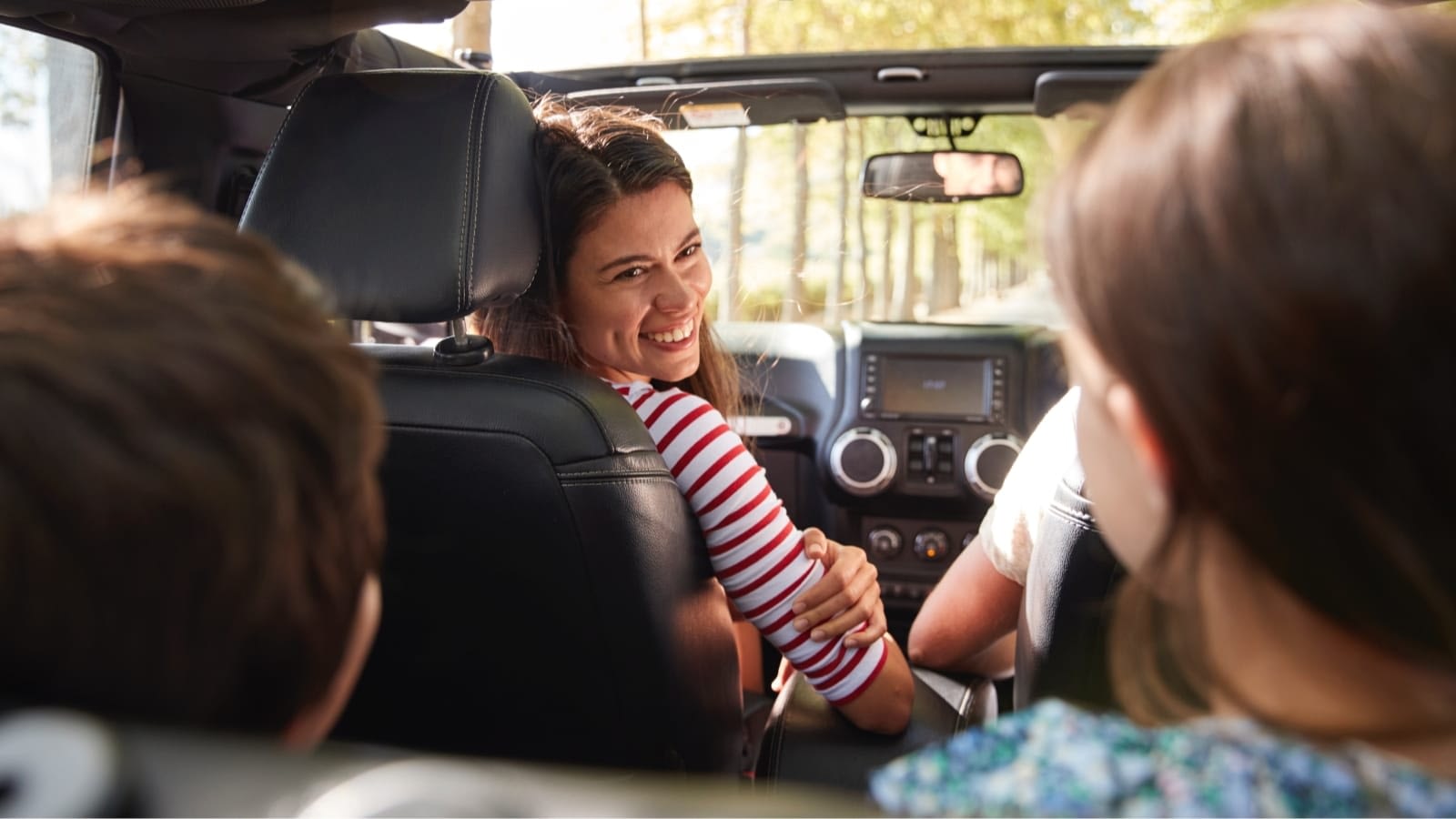 mother in jeep looking at kids in backseat