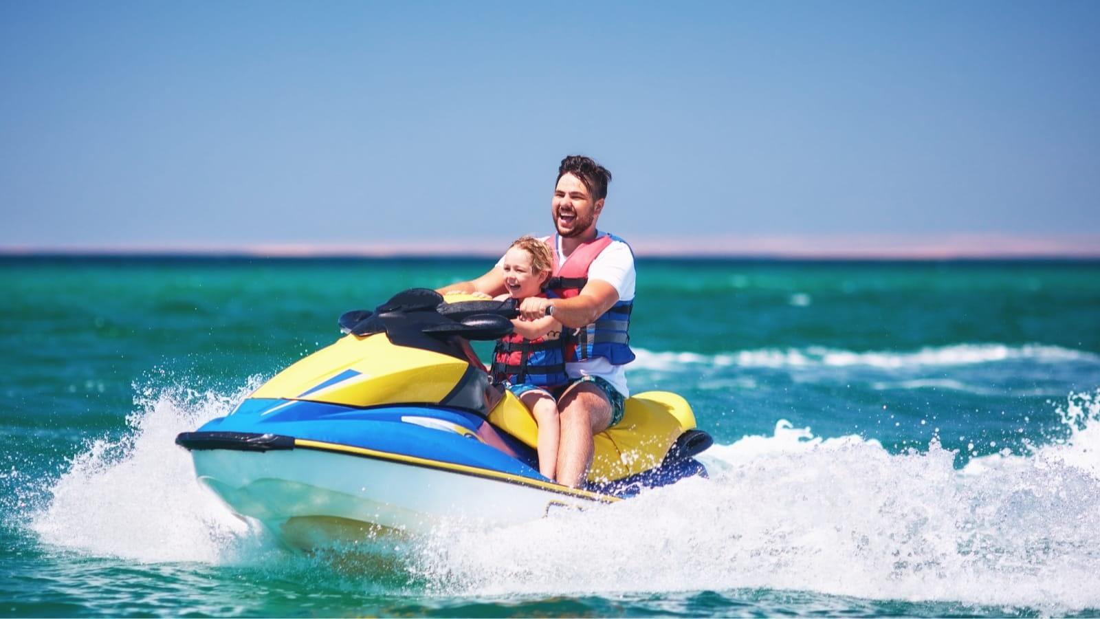 father and son riding a yellow and blue jet ski