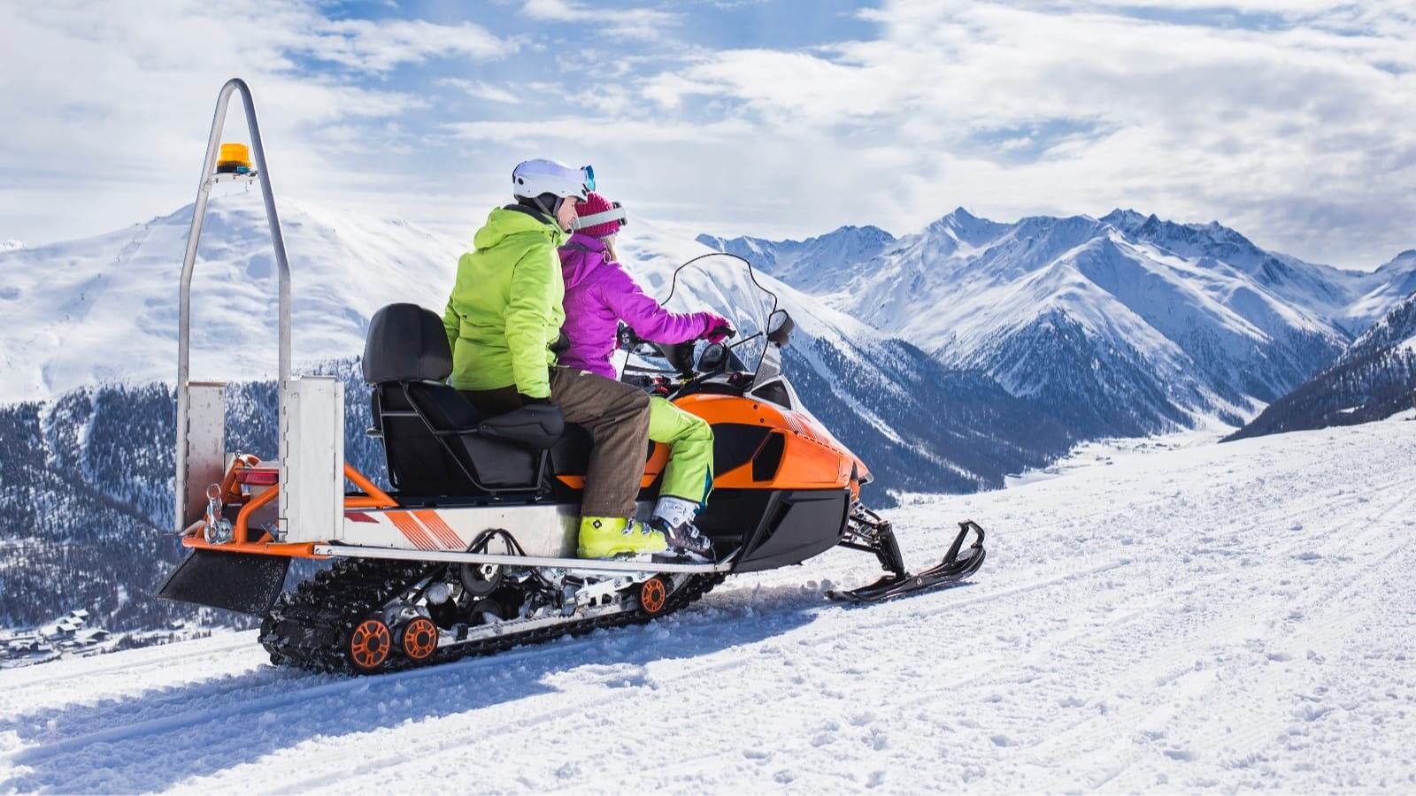 couple in bright jackets riding a snowmobile