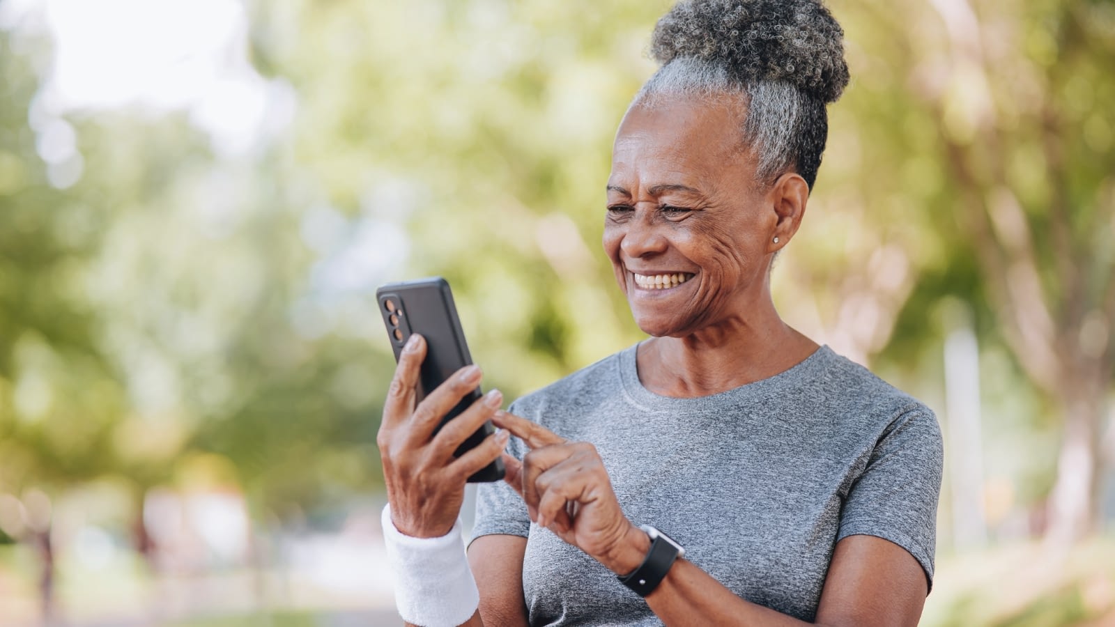 senior woman smiling while on a walk looking at app on her smart phone