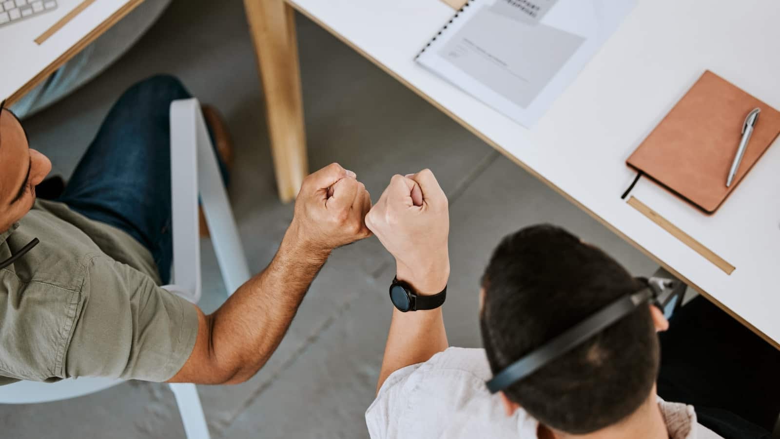 close-up of two male co-workers bumping fists