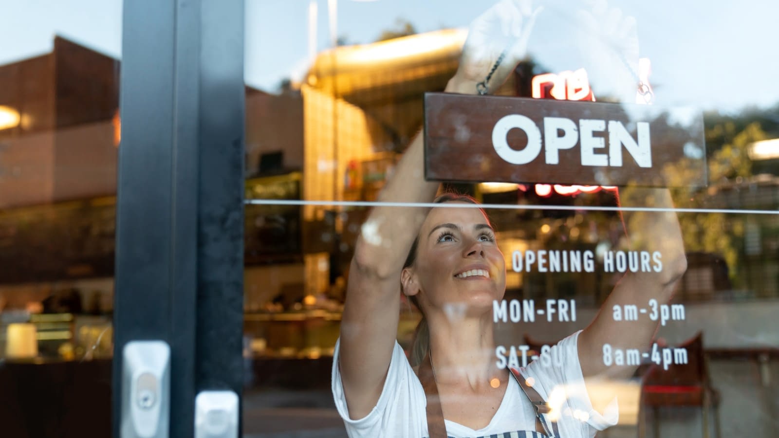 Small business owner with open sign business owner hanging open sign