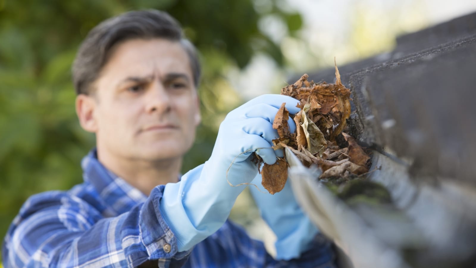 Man cleaning gutters outside