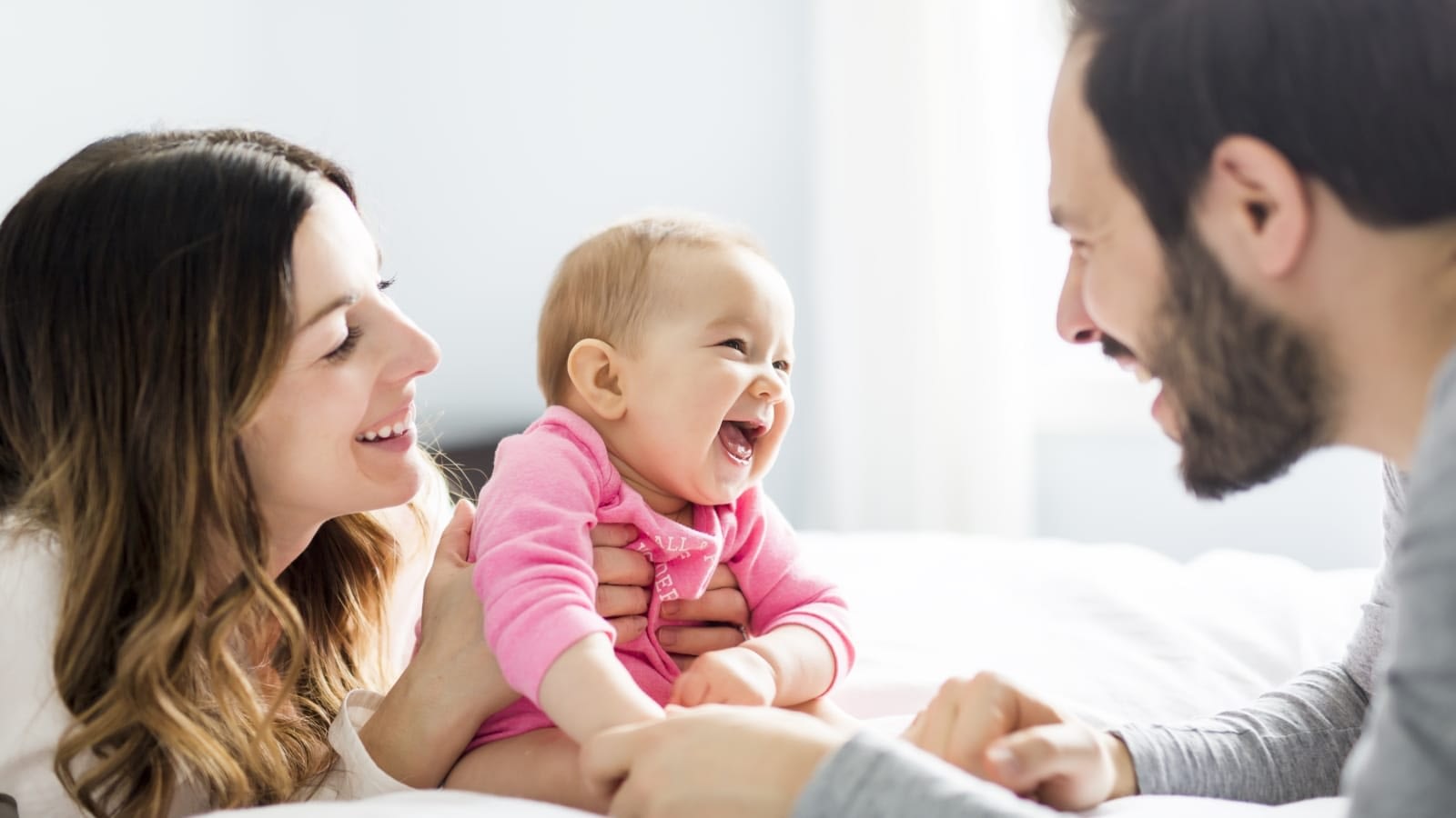 Mom, baby, and dad smiling at each other