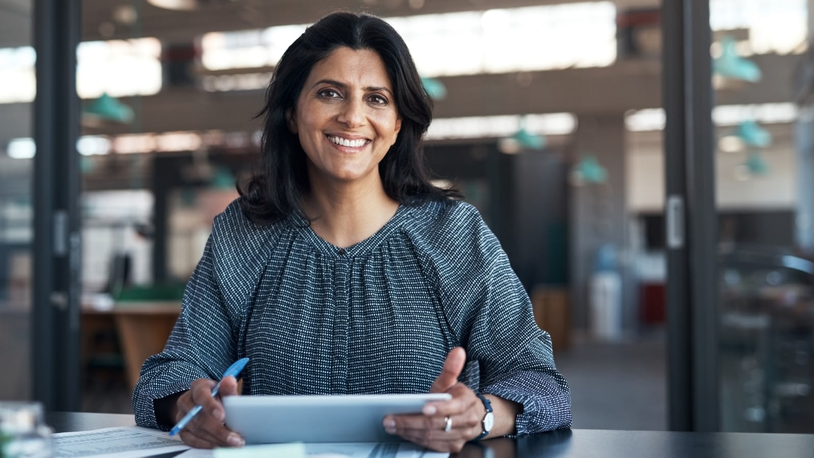 smiling female business owner sitting at desk with laptop