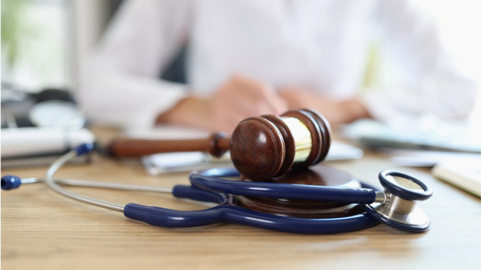 close-up of Dr. with judge gavel on top of stethoscope.