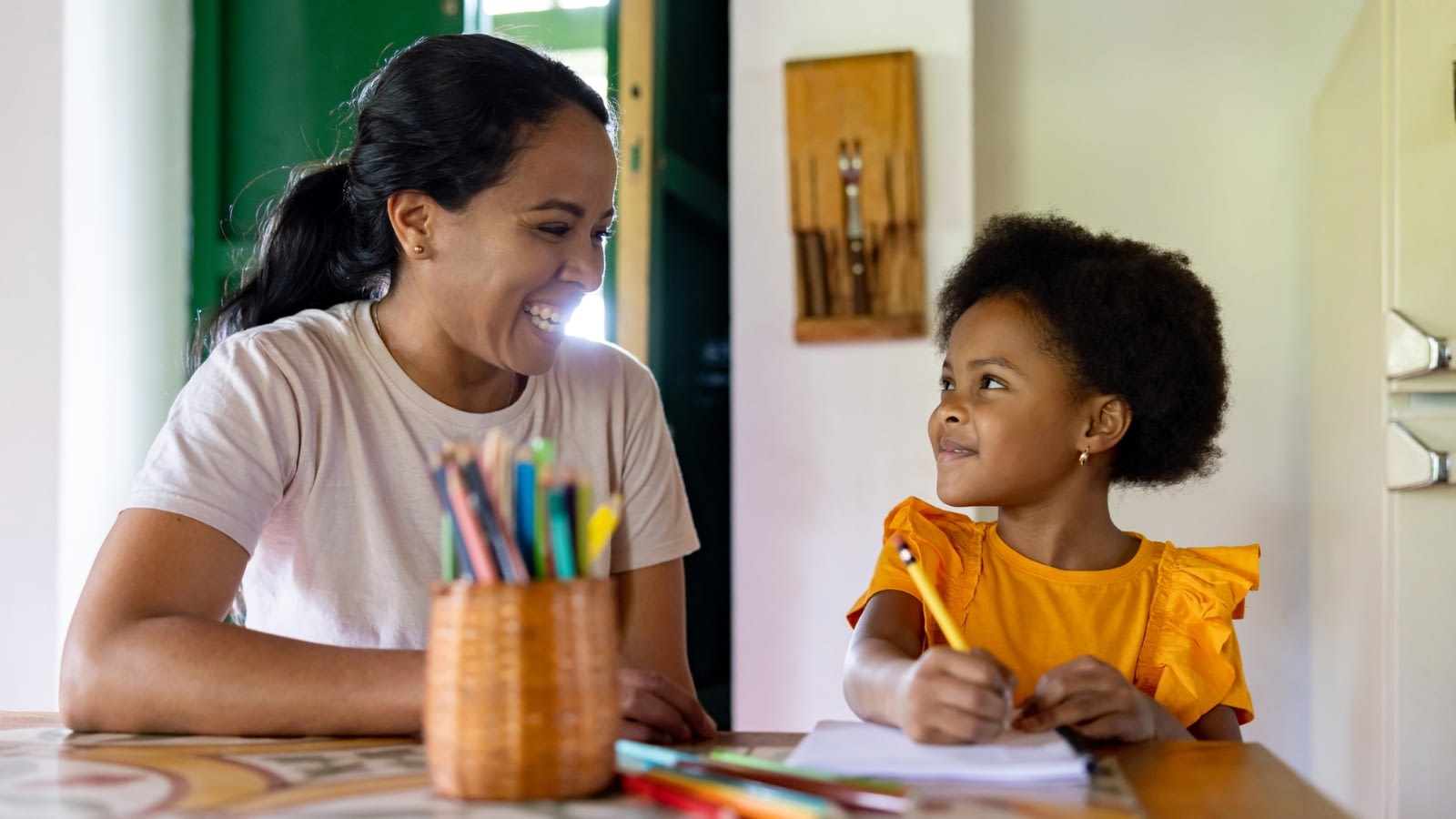 mother and daughter sitting at table smiling