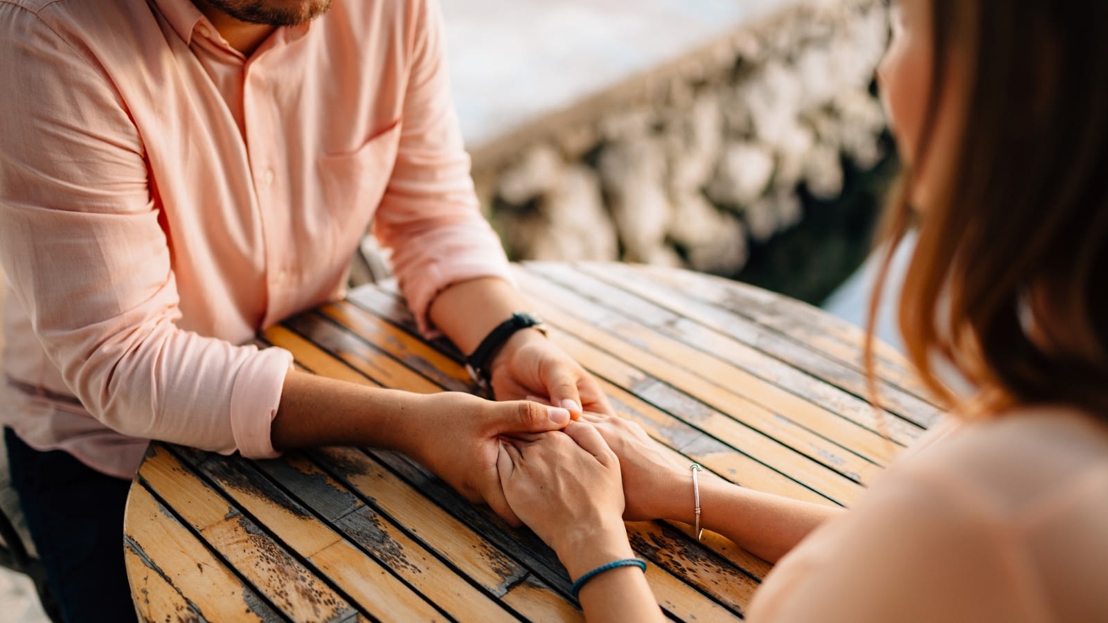 man and woman sitting at table holding hands