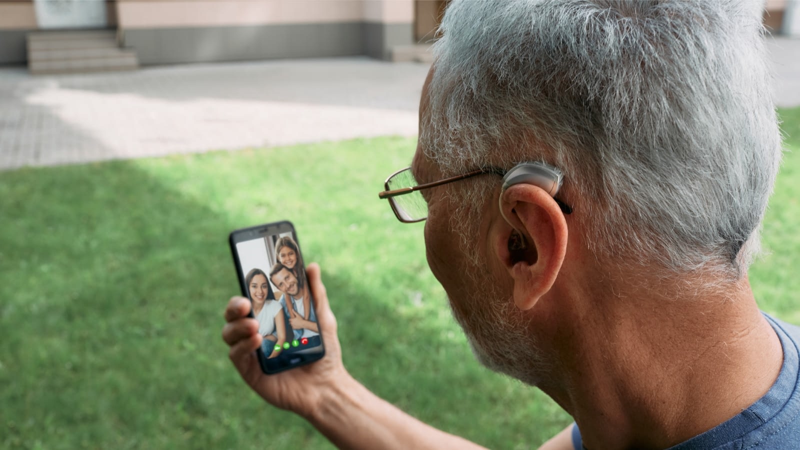 Senior man on FaceTime call with family wearing hearing aids