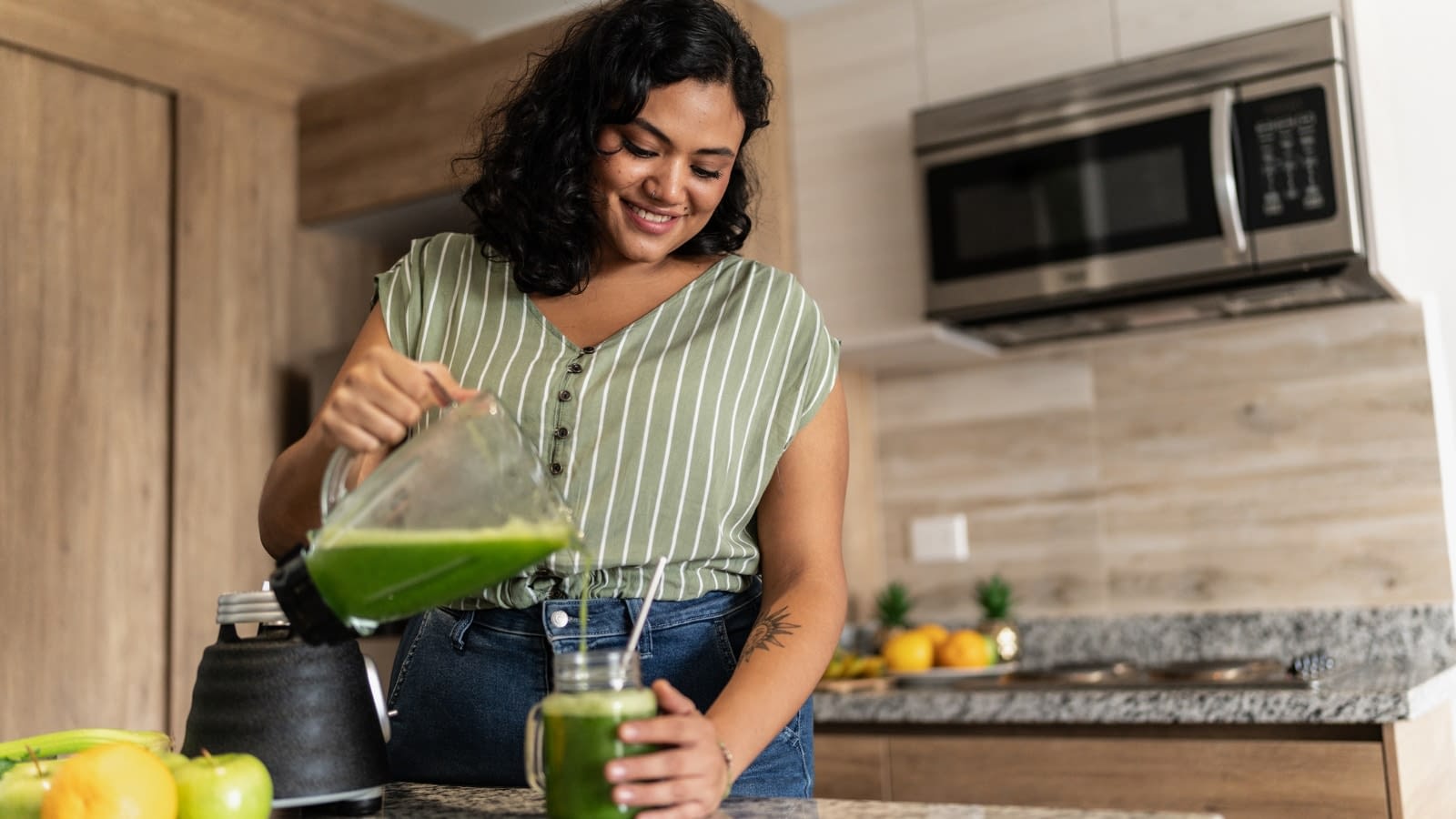 June 10 blog Healthy young woman making green smoothie in kitchen
