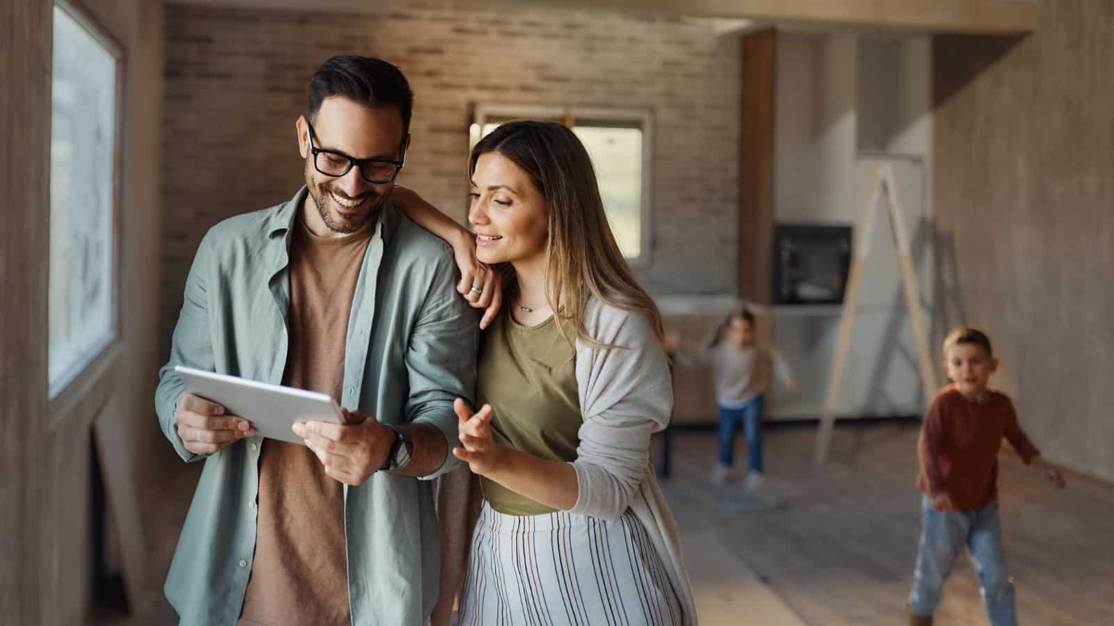 Young couple planning home renovation with children playing in background