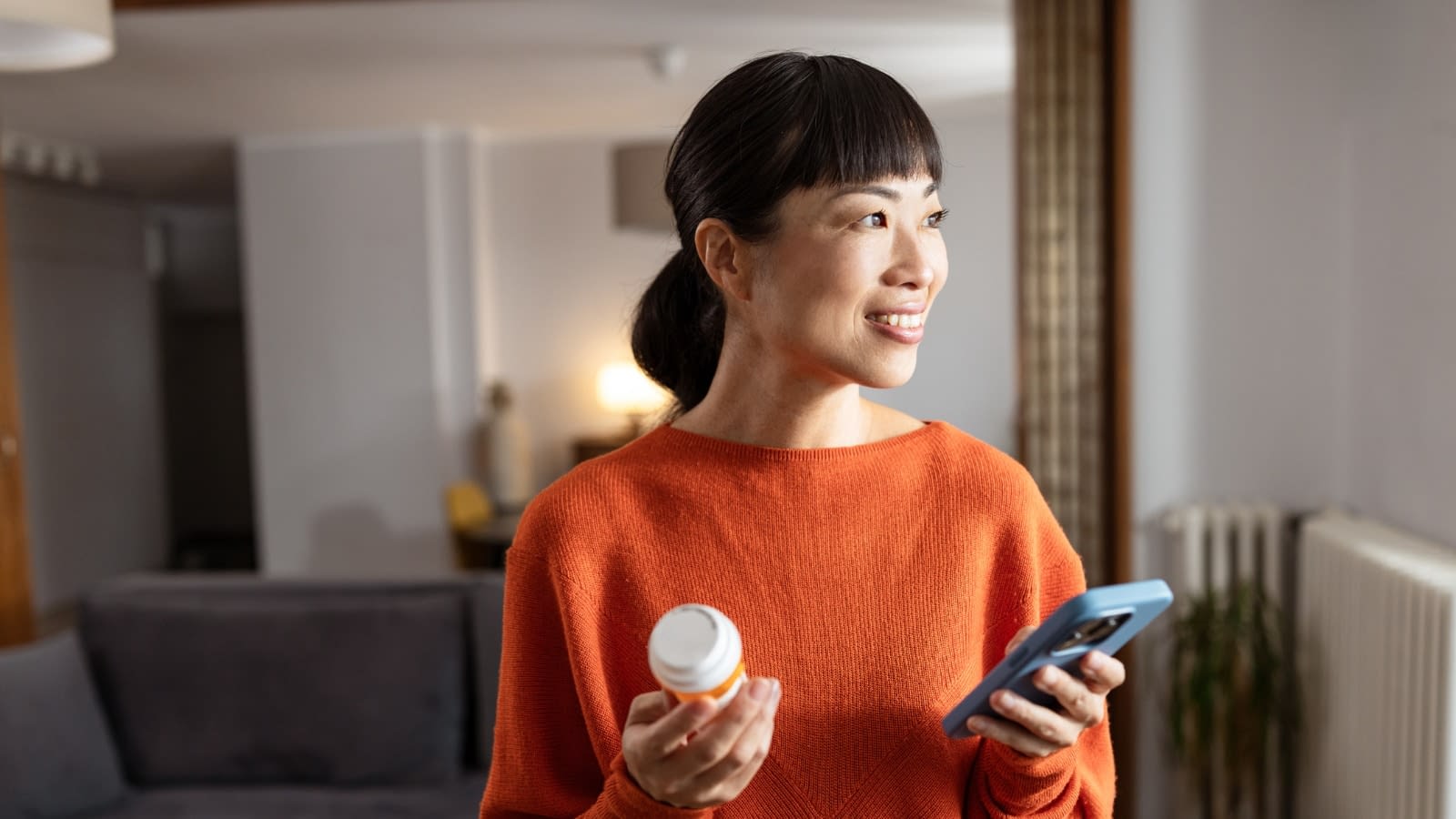 Oct 10 blog Asian woman on phone smiling holding prescription bottle