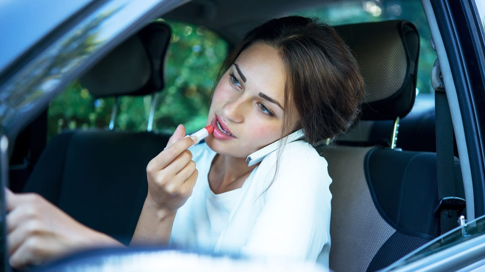 Distracted Driver Girl talking on the phone and putting on lipstick while driving