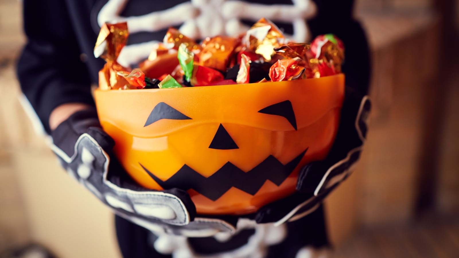 child in skeleton costume with a bowl of candy