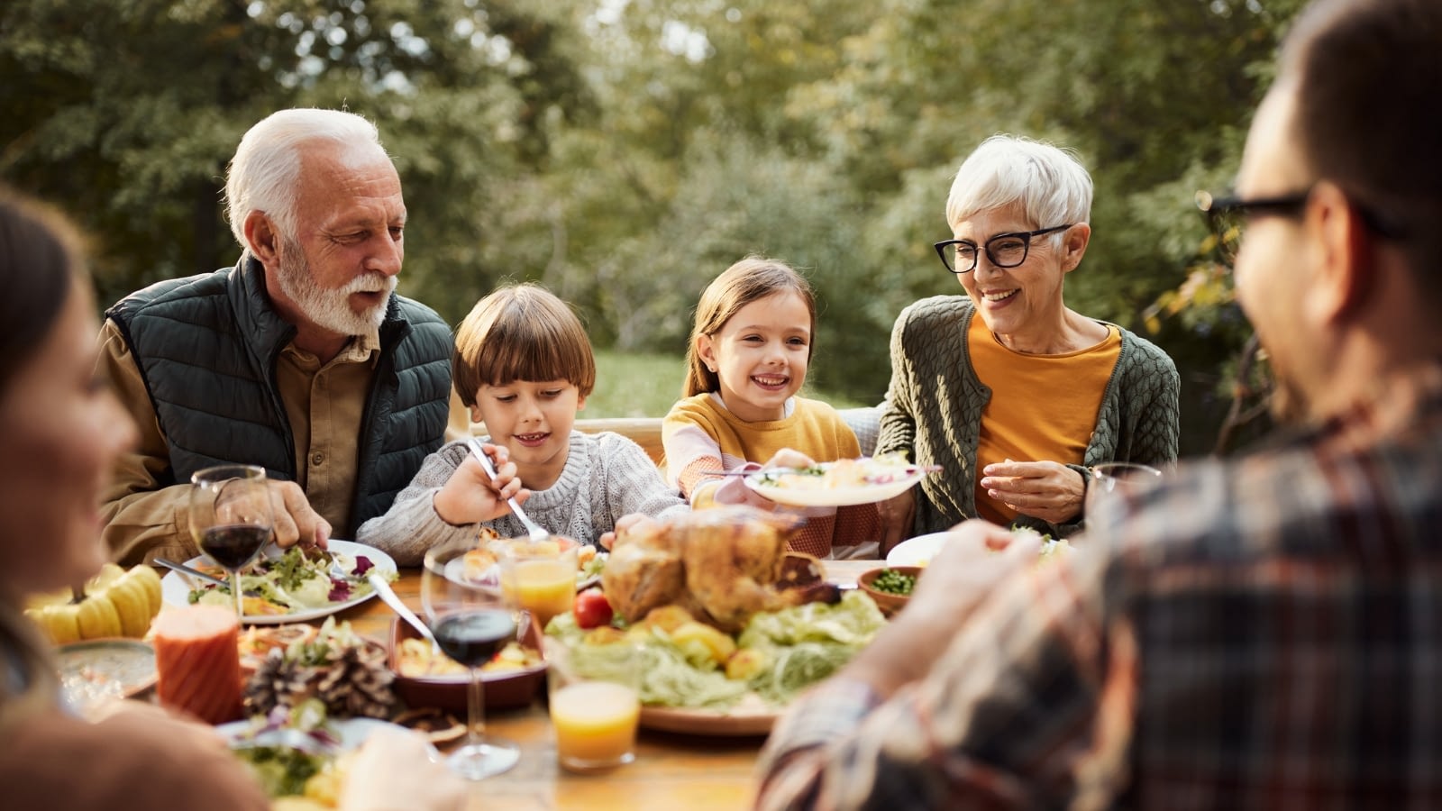 family sitting at outdoor thanksgiving table together.