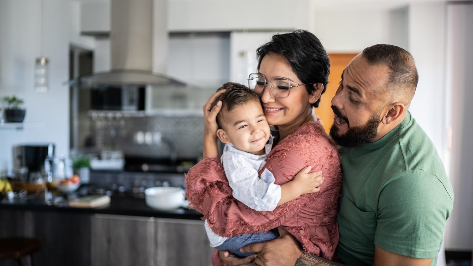 Young hispanic couple holding baby in house and smiling