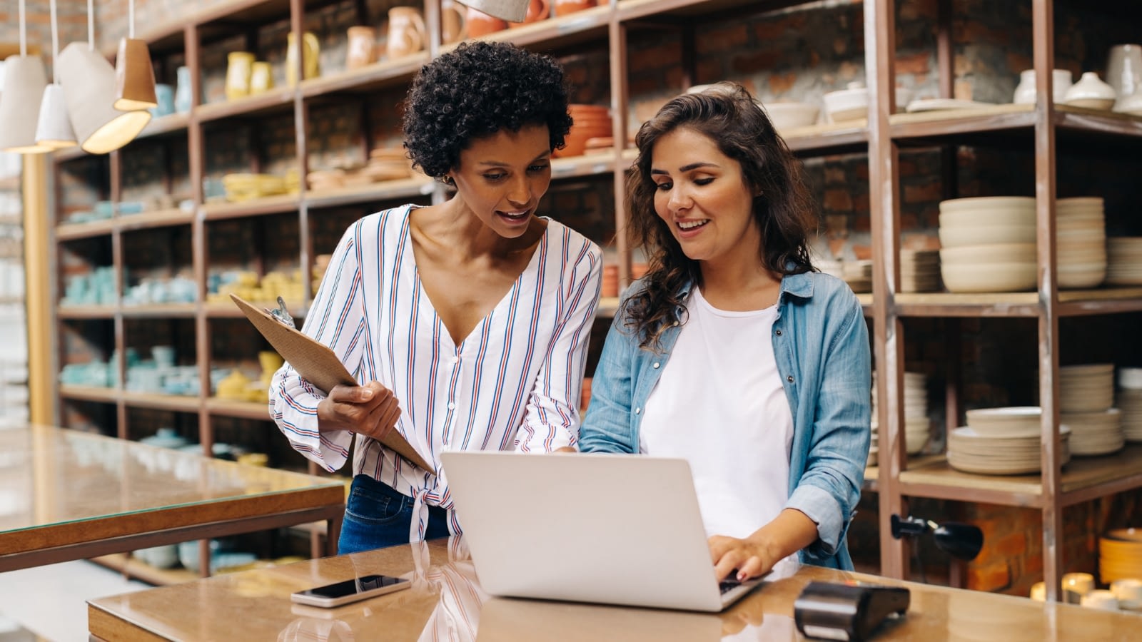 two young female business owners talking and looking at laptop