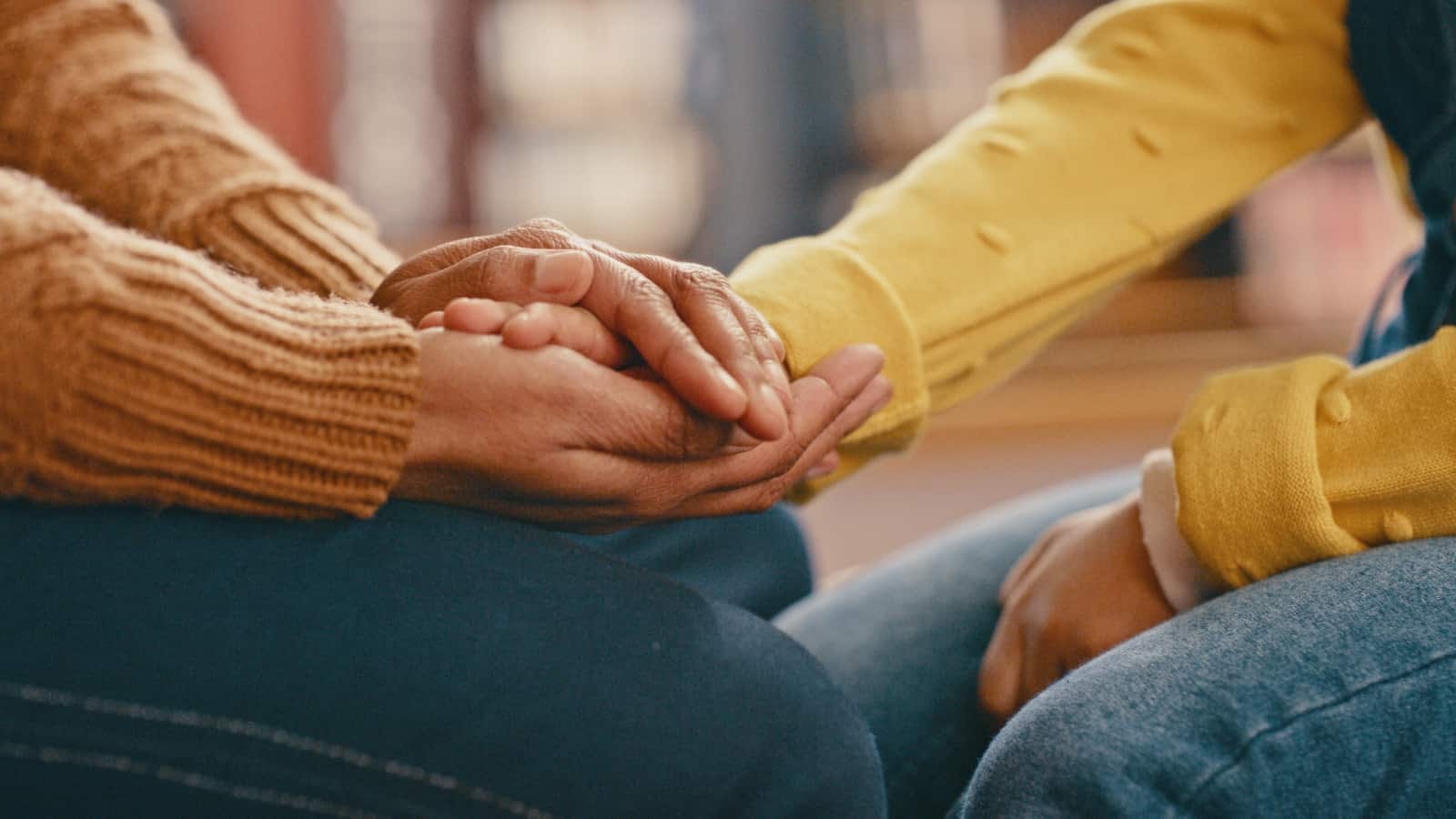 close-up of two women's hands in consoling hand-hold.